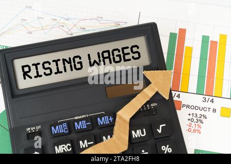 Concetto aziendale. Sui grafici aziendali è presente una calcolatrice sullo schermo con l'iscrizione - aumento dei salari Foto Stock