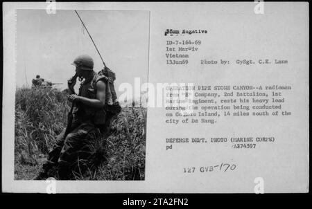 Un radiomano marino della e Company, 2nd Battalion, 1st Marine Regiment riposa mentre trasporta l'equipaggiamento durante l'operazione Pipe Stone Canyon sull'Isola Go Hoia, 14 miglia a sud di da Nang, il 13 giugno 1969. La fotografia mostra le comunicazioni militari e le operazioni sul campo durante la guerra del Vietnam. Foto Stock