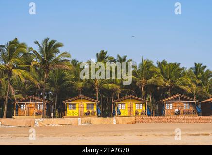 Capanne colorate sulla spiaggia di Agonda con palme a Goa, India Foto Stock