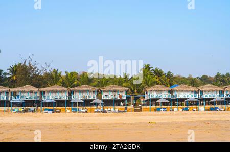 Capanne colorate sulla spiaggia di Agonda con palme a Goa, India Foto Stock