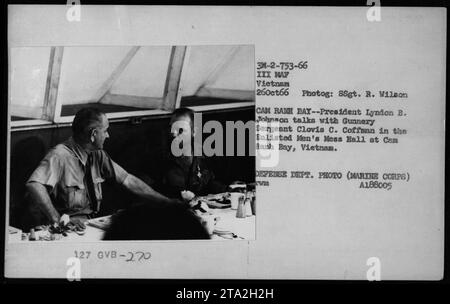 Il presidente Lyndon B. Johnson parla con il sergente Clovis C. Coffman nella sala arruolata Men's Mess Hall a Cam Ranh Bay, Vietnam. Questa fotografia cattura un momento di interazione tra Johnson e Coffman durante la loro visita a Cam Ranh Bay nell'ottobre 1966. Foto Stock