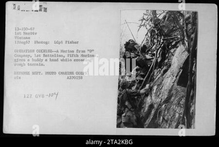 I Marines della compagnia "D", 1st Battalion, Fifth Marines, nell'operazione Cochise, aiutarono un altro Marine ad attraversare terreni impegnativi durante il combattimento il 17 agosto 1967, in Vietnam. Questa fotografia, scattata da LCpl Fisher, raffigura la dedizione e il sostegno condivisi tra i soldati durante il conflitto. Foto Stock