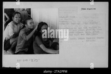 Le donne vietnamite si impegnano in una pratica tradizionale di raccogliere i pidocchi l'una dai capelli dell'altra. Questa immagine, scattata il 13 novembre 1969, mostra uno sguardo sulla vita civile durante la guerra del Vietnam. La foto mette in evidenza i costumi culturali e le attività degli abitanti del villaggio in Vietnam. Foto Stock