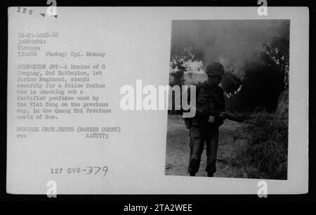 Un Marine della compagnia G, 2nd Battalion, 3rd Marine Regiment sta di guardia mentre un altro Marine ispeziona una posizione fortificata Viet Cong nella provincia di Quang Tri, vicino a Hue, in Vietnam, il 7 luglio 1966. L'immagine cattura l'uso di armi statunitensi da parte dei Marines durante l'operazione JAY. Foto del cpl. Mahony, Dipartimento della difesa. Foto Stock