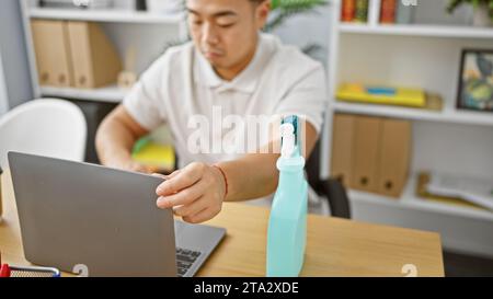 Giovane uomo professionista cinese rilassato che lavora diligentemente per pulire il suo portatile in un ambiente tranquillo Foto Stock