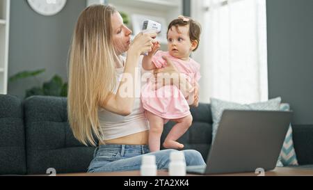 Madre e figlia che usano il computer portatile avendo una consultazione pediatrica online a casa Foto Stock