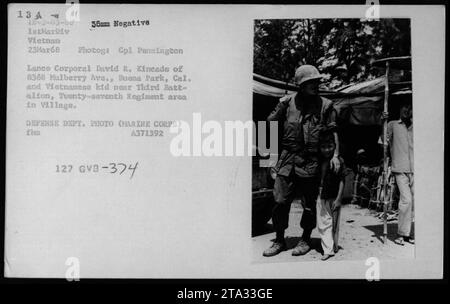 Il caporale David R. Kineade di Buena Park, California, parla con un bambino vietnamita vicino al terzo battaglione, nell'area del ventisettesimo reggimento in un villaggio durante la guerra del Vietnam. Questa fotografia è stata scattata il 23 marzo 1968 e fa parte della collezione Vietnamita Civilian Life - 1968. Foto Stock