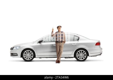 Un anziano che si appoggia su una nuova auto argentata e che punta in alto isolato su sfondo bianco Foto Stock