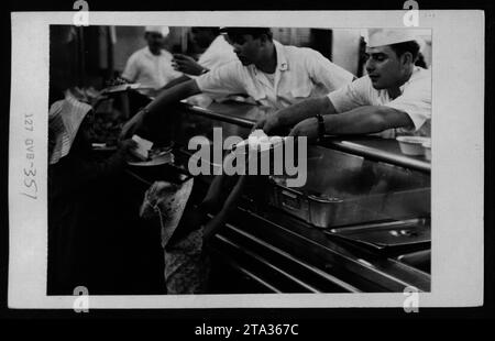 Immagine: La fotografia ha catturato un gruppo di rifugiati vietnamiti negli Stati Uniti l'8 maggio 1975. Nella foto, Claudia Cardinale, un'attrice italiana, viene vista in visita ai rifugiati insieme a figure di spicco come Nguyen Cao Ky, Rosemary Clooney e Betty Ford. La visita mirava a fornire sostegno e sensibilizzare sulla situazione dei rifugiati durante la guerra del Vietnam. Foto Stock