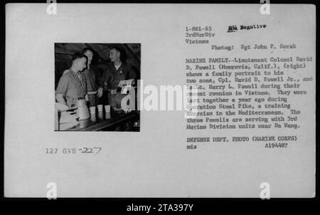 Il tenente colonnello David D. Powell mostra un ritratto di famiglia ai suoi figli, il colonnello David D. Powell Jr. E 1stLt. Harry L. Powell, durante una riunione a da Nang, Vietnam. La famiglia si è incontrata per l'ultima volta durante l'operazione Steel Pike, un'esercitazione. Fotografia del sergente John F. Gorak. Foto Stock