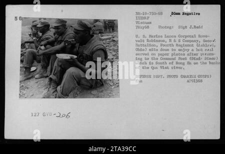 Il caporale di Marine Lance Roosevelt Robinson della R & S Company, Battaglione Secovi, Fourth Regiment (con sede ad Ashland, Ohio) è visto sedersi al Command Post (Dixie Dinar) accanto al fiume qua Viet, a sud di Dong ha durante la guerra del Vietnam. Si sta godendo un pasto caldo servito su piatti di carta dopo il ritorno dalle attività militari. Scattata il 7 maggio 1968, questa foto è stata scattata da SSgt J. Reid. [REPARTO DIFESA FOTO (CORPO MARINO) AT91368] Foto Stock