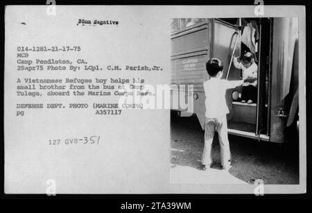 Un rifugiato vietnamita aiuta suo fratello minore dall'autobus all'arrivo a Camp Tulega, situato presso la base del corpo dei Marines Camp Pendleton, CALIFORNIA. La foto è stata scattata il 29 aprile 1975, durante una visita di Claudia Cardinale, Nguyen Cao Ky, Rosemary Clooney e Betty Ford. Fotografo: LCpl. C.M. Parish Jr. Foto Stock