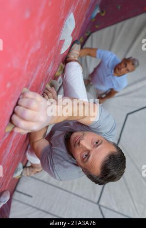 uomo che sale da una parete per arrampicata al coperto Foto Stock