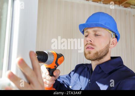 uomo con trapano elettrico che lavora a casa Foto Stock