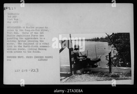 Nel maggio 1965, un Marine della 3rd Marine Amphibious Force controlla il ponte ferroviario sul fiume Song-an-Tan, un'importante via di comunicazione che collega Danang alle città meridionali durante la guerra del Vietnam. Foto Stock