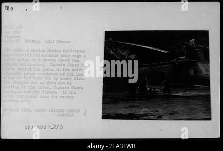 Equipaggio addetto alla manutenzione del Marine Medium Helicopter Squadron-165 che sta montando un'imbracatura di sollevamento su un elicottero CH-46 Sea Knight. Il capitano James F. Pleva atterrò l'elicottero danneggiato in un fiume a nord-ovest di Chu Lai dopo il fuoco nemico. L'elicottero era in fiamme e lo sbarco nel fiume estinse le fiamme. L'elicottero è stato recuperato in seguito. Foto del Dipartimento della difesa, 12 maggio 1967. Foto Stock
