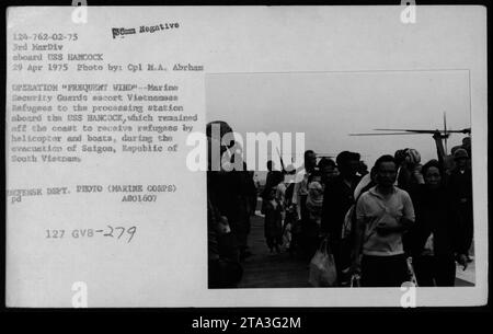 Le guardie di sicurezza marine scortano i rifugiati vietnamiti alla stazione di trattamento a bordo della USS Hancock durante l'operazione Frequent Wind, l'evacuazione di Saigon il 29 aprile 1975. La USS Hancock accolse i rifugiati in elicottero e in barche al largo della costa. Questa foto è stata scattata dal Cpl M.A. Abrham ed è una foto del Dipartimento della difesa. Foto Stock