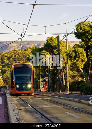 Tram che passa davanti alla città nei colori del tramonto Foto Stock