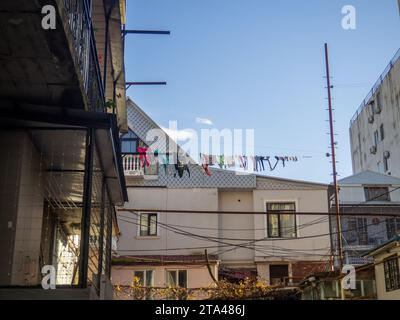 La lavanderia è asciugata su una lunga fila per strada. Vita locale in Asia. Balconi e cortili di Batumi. Asciugare i vestiti al sole e al vento Foto Stock