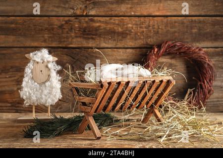 Manger con manichino di bambino e pecora su sfondo di legno. Concetto di storia di Natale Foto Stock