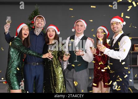Giovani colleghi con champagne e coriandoli che festeggiano il nuovo anno alla festa aziendale in ufficio Foto Stock