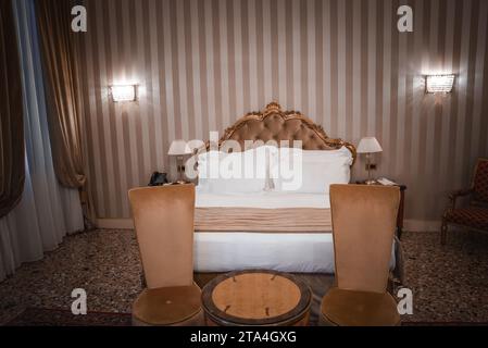 Lussuosa ed elegante camera da letto con letto king size, sedie e combinazione di colori neutri Foto Stock