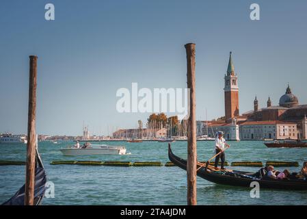 Vista panoramica del Canal grande con gondole nere che galleggiano sull'acqua blu a Venezia, Italia Foto Stock