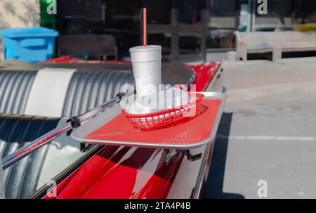 vassoio per alimenti su un'auto d'epoca trasformabile red con tazza per bevande in polistirolo, cannuccia rossa e supporto per hotdog in polistirolo. Foto Stock