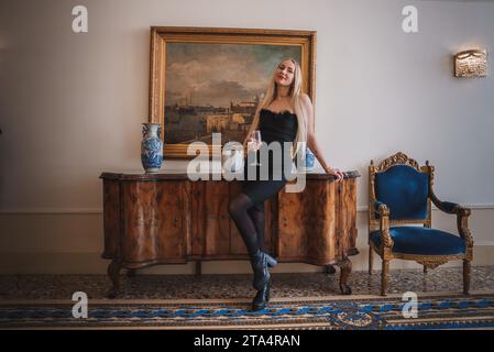 Elegante donna in abito nero in piedi di fronte a un dipinto della collezione di Venezia. Foto Stock