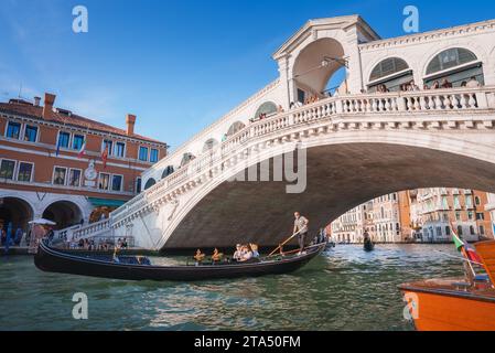 Iconico Ponte di Rialto a Venezia con la gondola che passa sotto in una vibrante atmosfera estiva Foto Stock