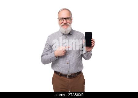 moderno uomo d'affari maturo e dai capelli grigi con barba e baffi in camicia e pantaloni che tiene in avanti lo schermo dello smartphone Foto Stock