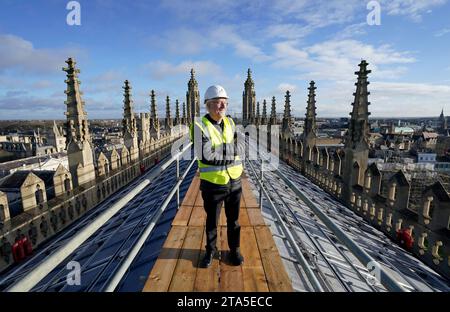 Stephen Cherry, decano della cappella del King's College, guarda l'installazione di 438 nuovi pannelli solari fotovoltaici sul tetto della cappella recentemente restaurata del King's College di Cambridge. I pannelli soddisferanno il 100% del fabbisogno energetico della Cappella e ridurranno le emissioni di carbonio del Collegio di oltre 27 tonnellate ogni anno. Data immagine: Martedì 28 novembre 2023. Foto Stock