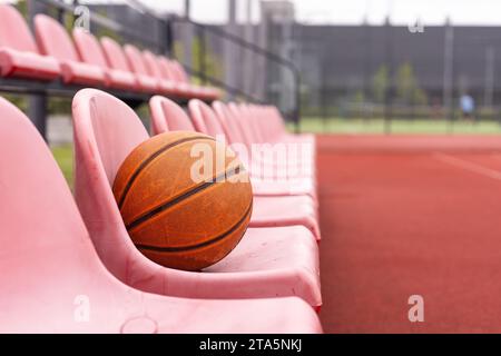 Il basket usato in primo piano si trova su un campo di basket vuoto con uno sfondo sfocato. Foto Stock