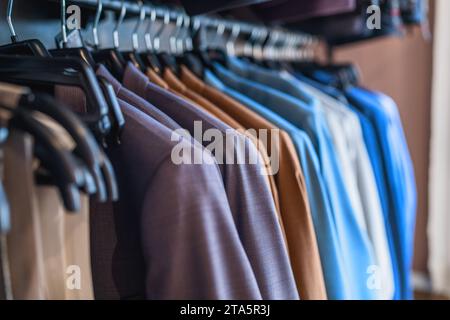 Fila di abiti colorati su appendini in un negozio di abbigliamento Foto Stock