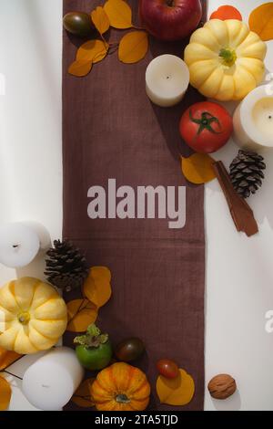 Idee creative per la fotografia di concetto autunnale e il ringraziamento. Mini zucche decorate con foglie secche, pomodori maturi e noci secche su un bac bianco Foto Stock