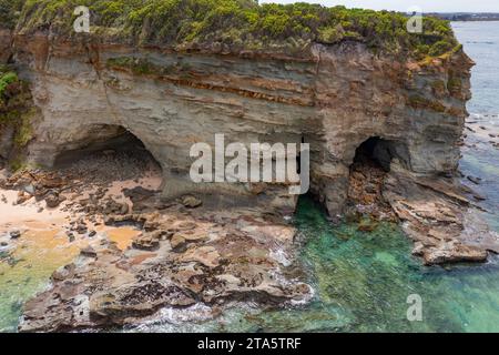 Vista aerea delle grotte costiere in una scogliera rocciosa che si protende verso il mare a Inverloch a Gippsland, Victoria, Australia. Foto Stock