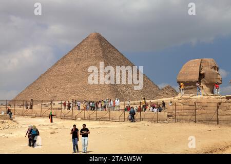 Una piramide e una grande sfinge nel quartiere di Giza del Cairo. I turisti si trovano di fronte alla piramide. Le piramidi sono nella lista del patrimonio mondiale dell'UNESCO. Foto Stock