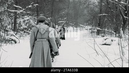 Esercito a Marching. Uomini vestiti da soldati della Guardia Bianca dell'Esercito Imperiale Russo in marcia nella Foresta invernale innevata della Guerra civile russa. Storico Foto Stock