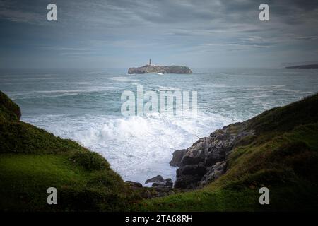 Immagine di un faro sulla costa settentrionale della Spagna, nel Mar Cantabrico. In una nuvolosa giornata autunnale da una scogliera. Foto Stock