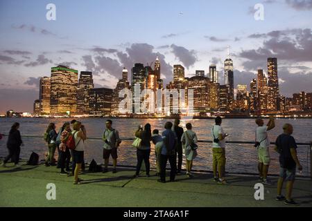 New York, USA - 9 giugno 2018: Persone al Brooklyn Bridge Park godendo la vista serale del quartiere finanziario di Lower Manhattan. Foto Stock