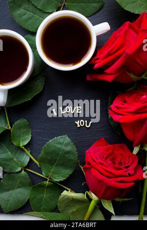 L'iscrizione ti amo su sfondo nero, caffè, rose rosse, primo piano Foto Stock