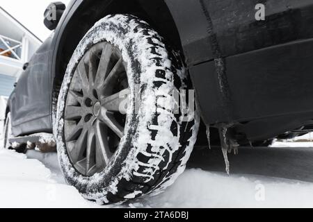 Foto ravvicinata di una ruota di un SUV su uno pneumatico da neve con borchie metalliche Foto Stock