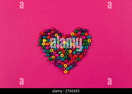 Vista dall'alto di un cuore colorato a forma di sfondo per San Valentino. Cuore di perle multicolore. Vista dall'alto. Foto Stock