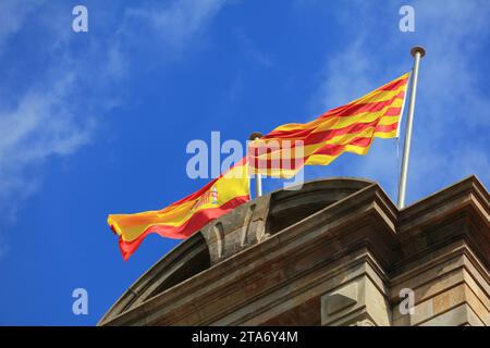 Bandiera della Spagna e bandiera della Catalogna fianco a fianco nel vento in cima al Parlamento della Catalogna a Barcellona. Foto Stock