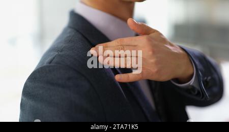 Uomo d'affari in tuta d'affari spazzolando via la polvere o forfora dal suo primo piano della spalla Foto Stock