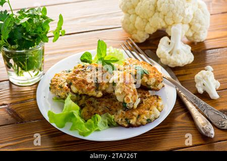 cotolette di cavolfiore fritte vegetariane, in un piatto su un tavolo di legno. Foto Stock