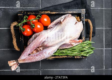 Selvaggina uccello guineafowl crudo, faraona pronto per la cottura. Sfondo nero. Vista dall'alto. Foto Stock