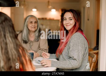 Ritratto di una donna sorridente con madre e figlia sedute a casa Foto Stock