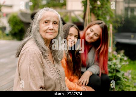 Ritratto di donna anziana seduta con figlia e nipote nel patio Foto Stock