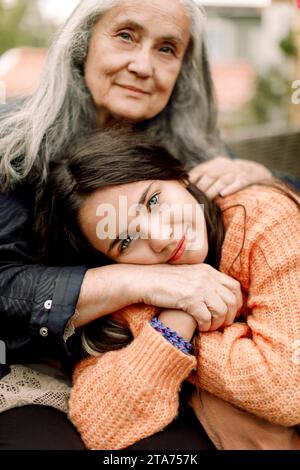 Ritratto di una ragazza sorridente che tiene per mano e abbraccia la nonna Foto Stock
